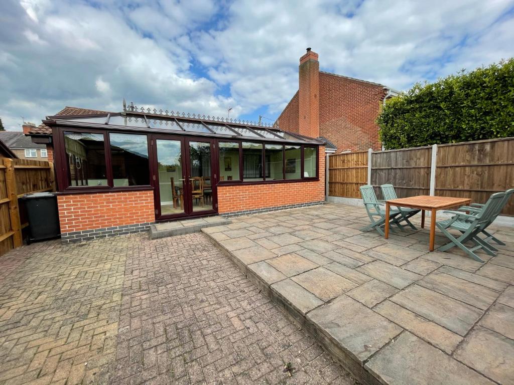 un patio con tavolo, sedie e un edificio di Redd Lodge Heart of the National Forest a Thringstone