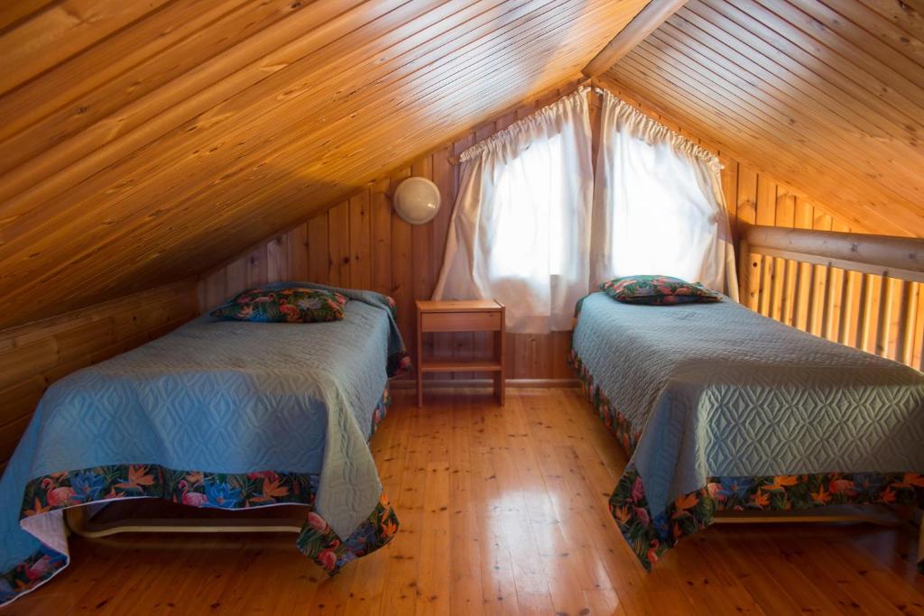 Cette chambre mansardée comprend 2 lits et une fenêtre. dans l'établissement Villa Omena at MESSILA ski & camping, à Hollola