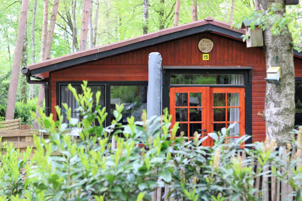 uma cabana na floresta com uma porta vermelha em Het Zenhuisje em Lanaken