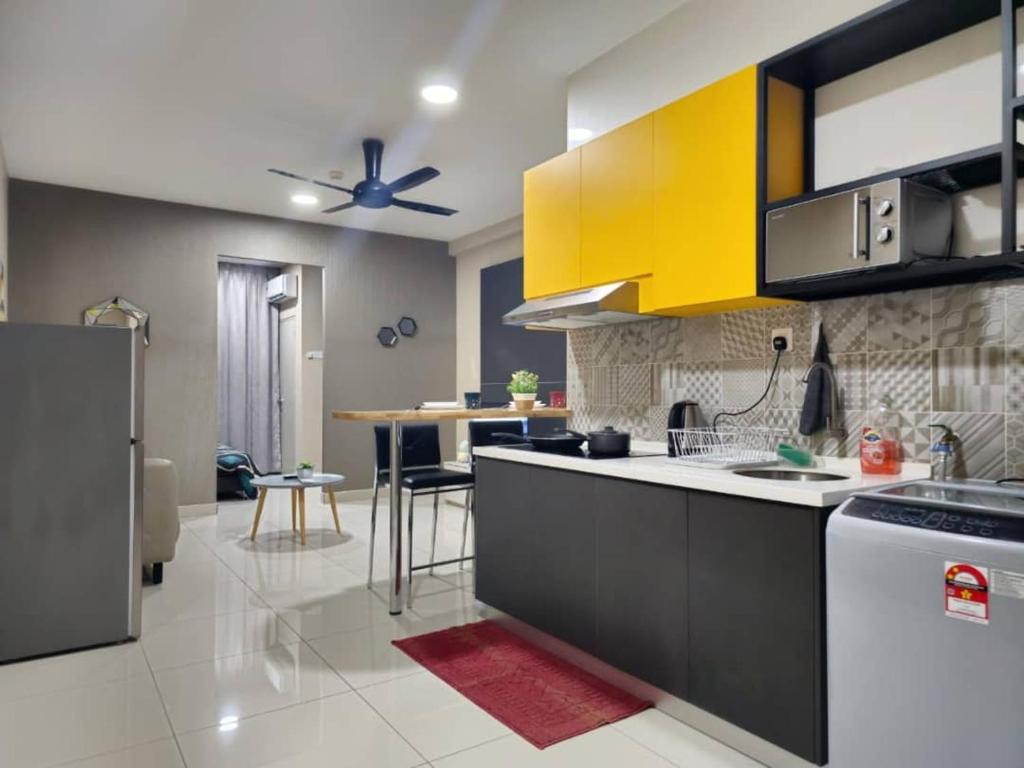 une cuisine avec des armoires jaunes et noires et une table dans l'établissement Liberty Arc Studio 舒适和10分钟到 KL, à Batu Empat