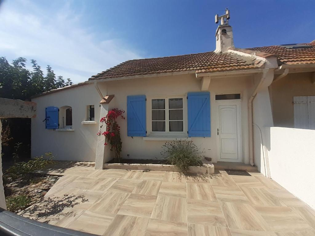 une maison blanche avec des portes bleues et une allée. dans l'établissement Maison bord de mer, à Saint Cyprien Plage