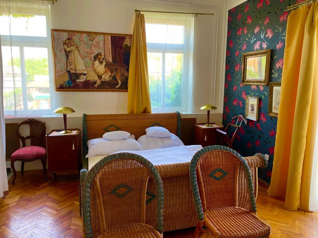 a bedroom with a bed and two chairs at Villa Luca in Mosonmagyaróvár