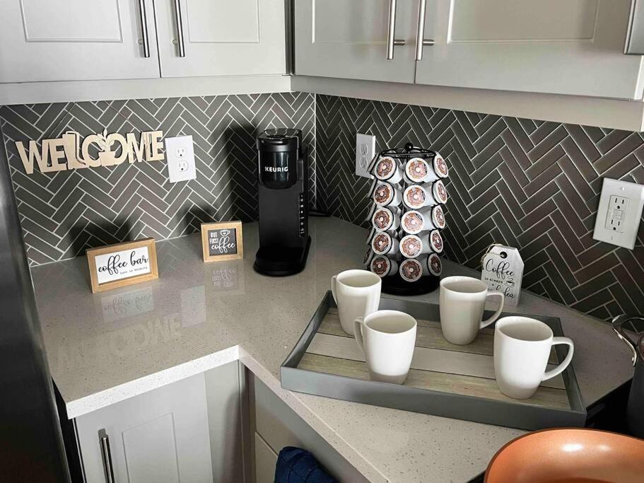 Elegant & Luxurious Modern Apartment with Southern Charm في فورت وورث: طاولة مطبخ مع أكواب وآلة صنع القهوة