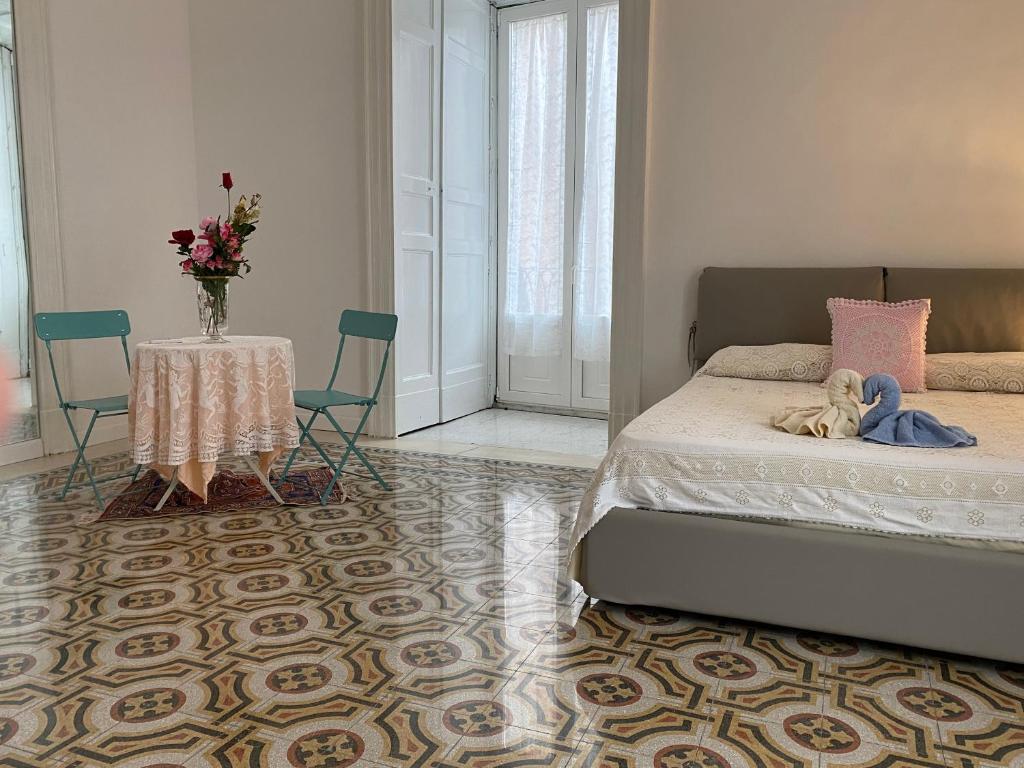 een slaapkamer met een bed en een tafel en stoelen bij Casa di Rita in Catania