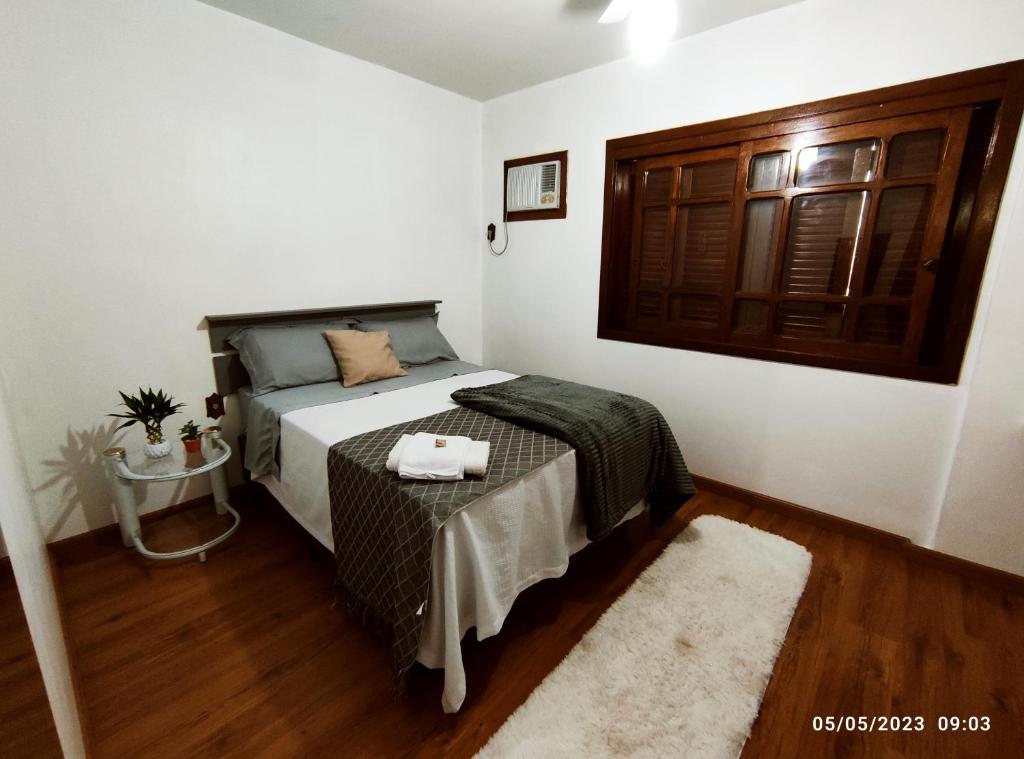 a bedroom with a bed with a table and a door at Pousada com vista para o Cristo 1 in Encantado