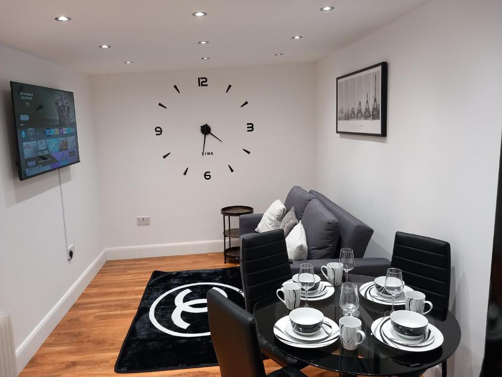 uma sala de estar com uma mesa e um relógio na parede em Heronsgate GH013 em Erith