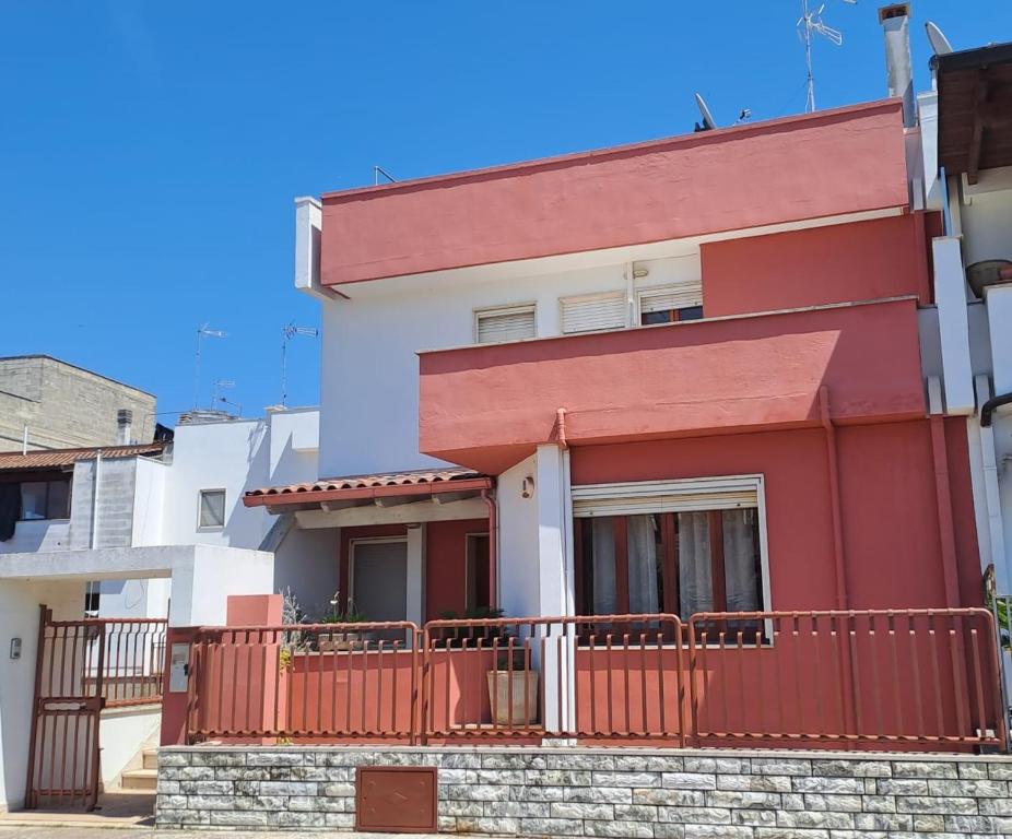 una casa rossa e bianca con una recinzione di Villa Iris a Galatone