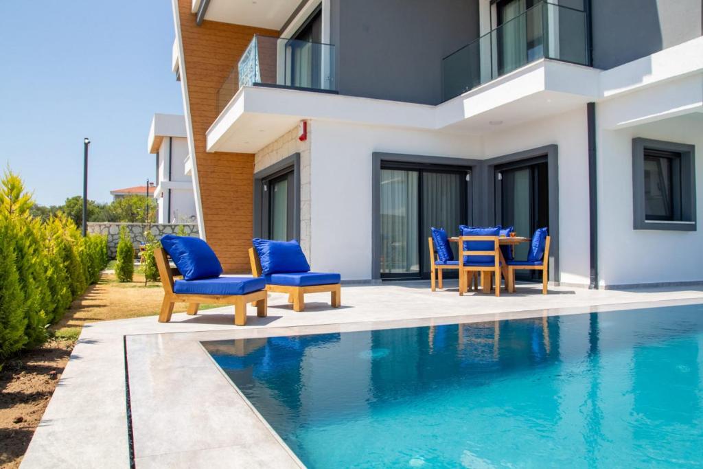 un patio con sillas azules y una mesa junto a la piscina en Amazing Villa with Private Pool in Alacati Cesme, en Alacati