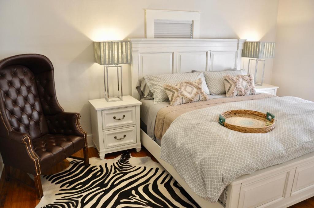 een witte slaapkamer met een bed en een stoel bij Cozy 2 BDRM Vacation Rental - 1 Mile to Dtwn Rapid City in Rapid City