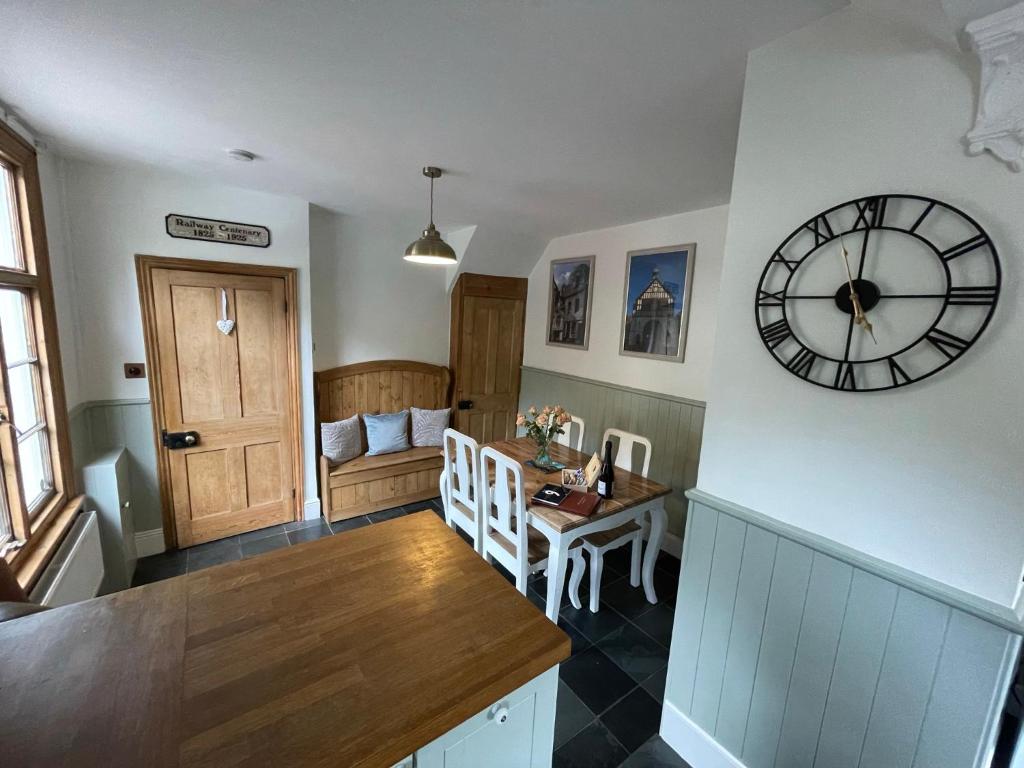 a kitchen with a clock on the wall and a table at The Railway Cottage Bridgnorth in Bridgnorth