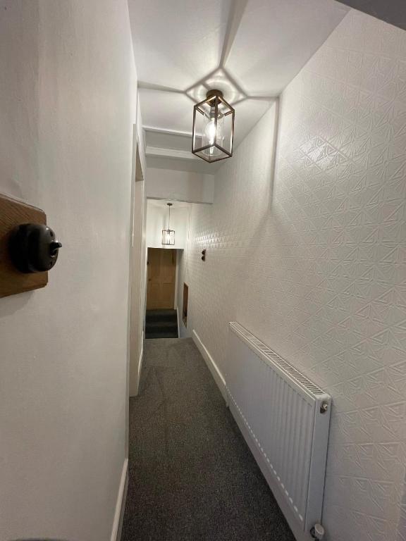 a hallway with a white wall and a light fixture at The Railway Cottage Bridgnorth in Bridgnorth