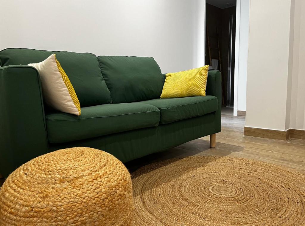- un canapé vert avec deux oreillers jaunes dans le salon dans l'établissement Antibes centre, 3 Chambres, 2 Salles de bain, Clim, Terrasse, Wifi, à Antibes