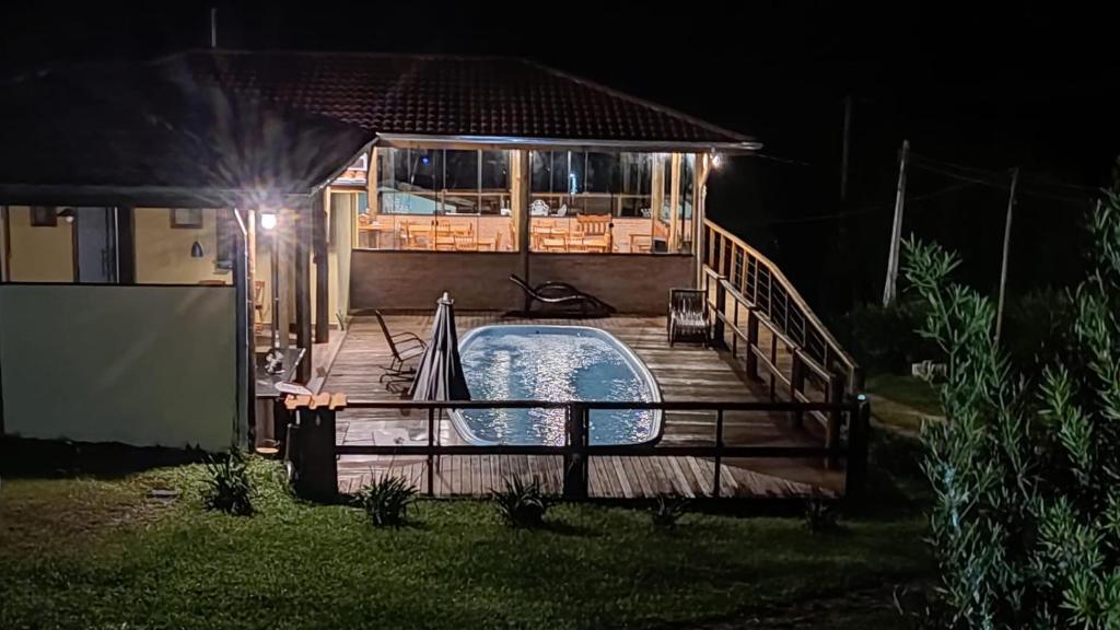 a swimming pool on a wooden deck at night at Pousada São Miguel in Cunha