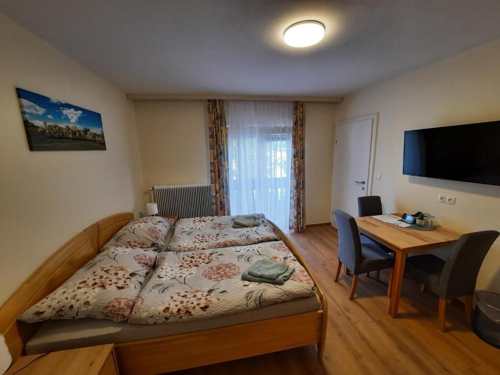 Habitación pequeña con cama, escritorio y TV. en Kirchenwirt en Kaumberg