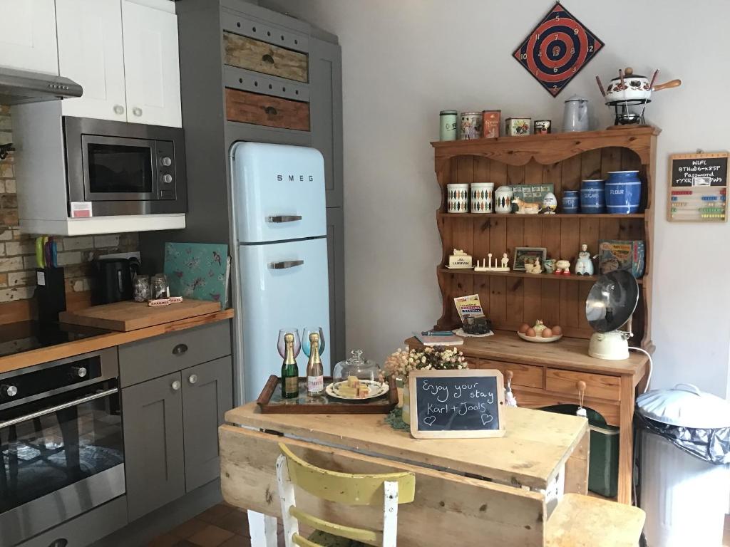 uma cozinha com uma mesa e um frigorífico azul em Holly cottage Wold Newton, near Yorkshire coast em Wold Newton