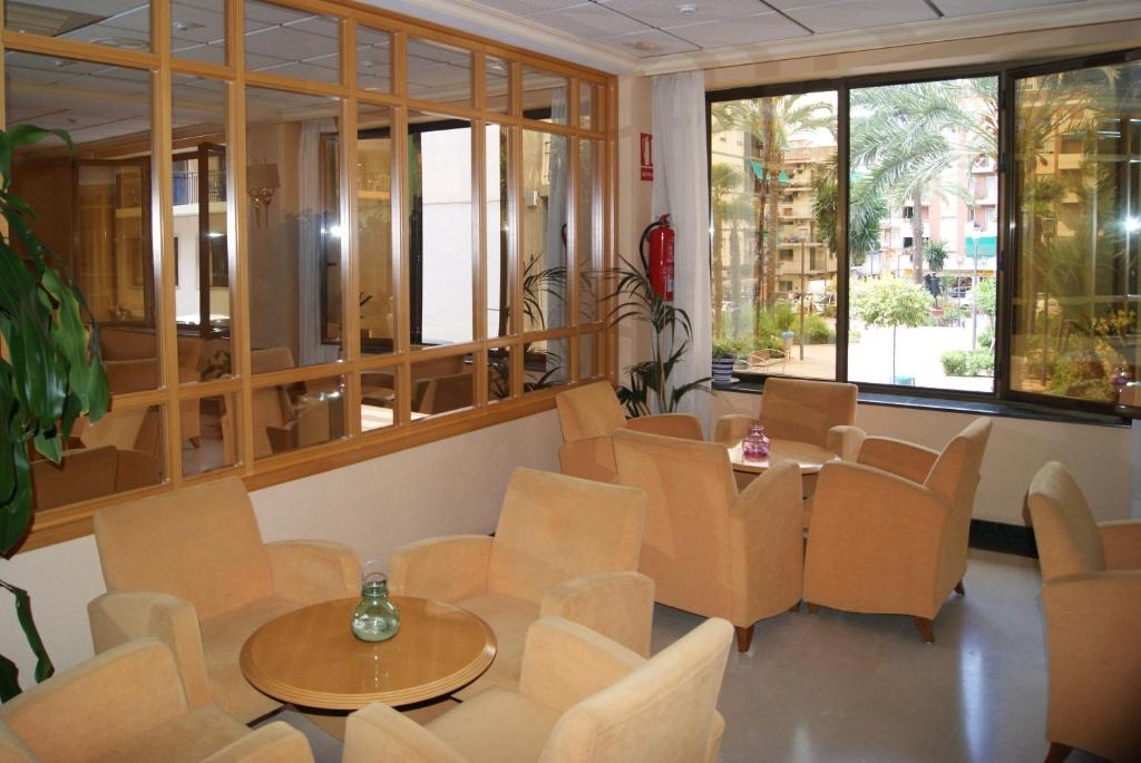 Zimmer mit Stühlen, Tischen und Fenstern in der Unterkunft Rosabel in Benidorm