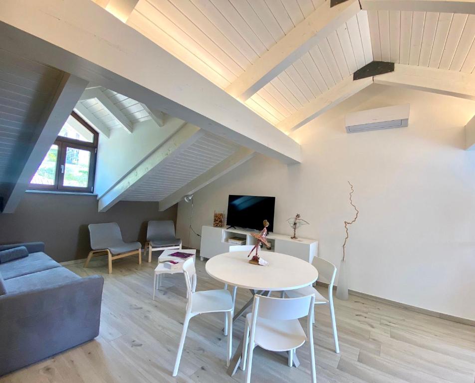 sala de estar con mesa, sillas y TV en Casa di Nuvola -Residenza Lavinia -, en Monforte dʼAlba