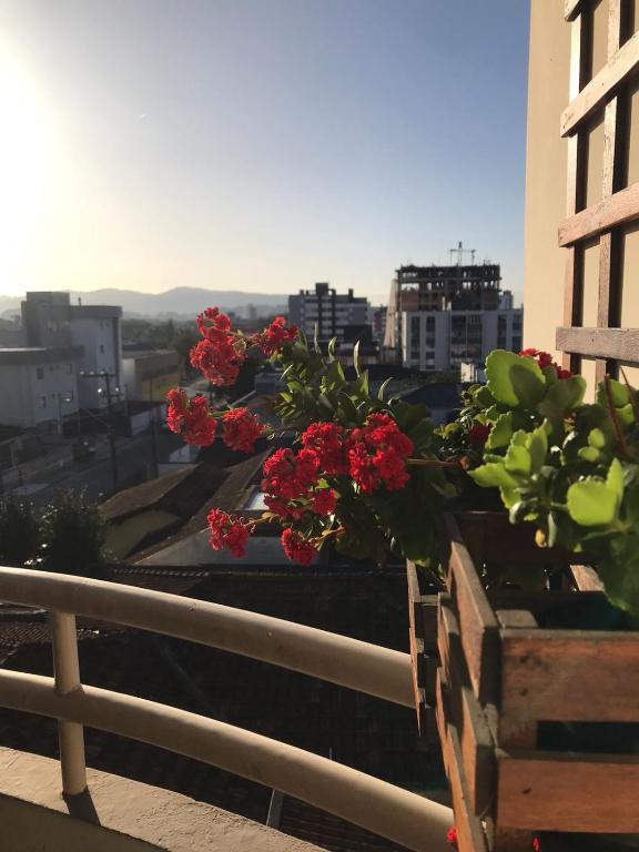 a view of a city with red flowers on a balcony at Apartamento completo em Joinville no Costa e Silva - Há 50 km das Praias SC in Joinville