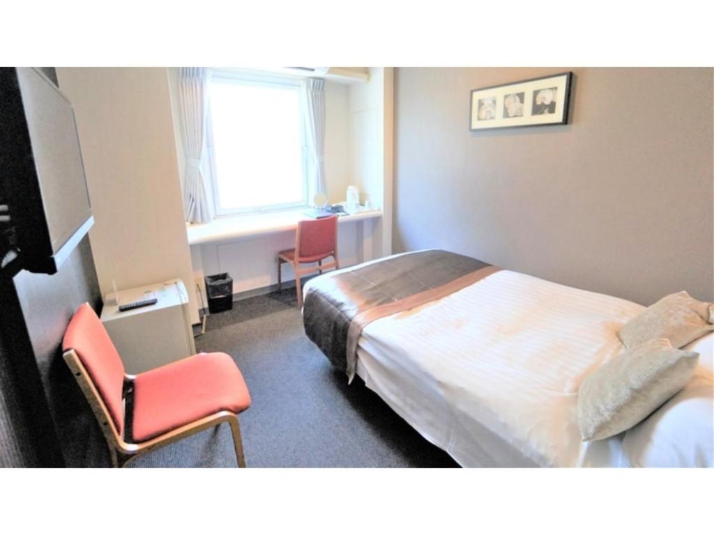 een hotelkamer met een bed en twee stoelen bij Hotel Areaone Okayama - Vacation STAY 32493v in Okayama