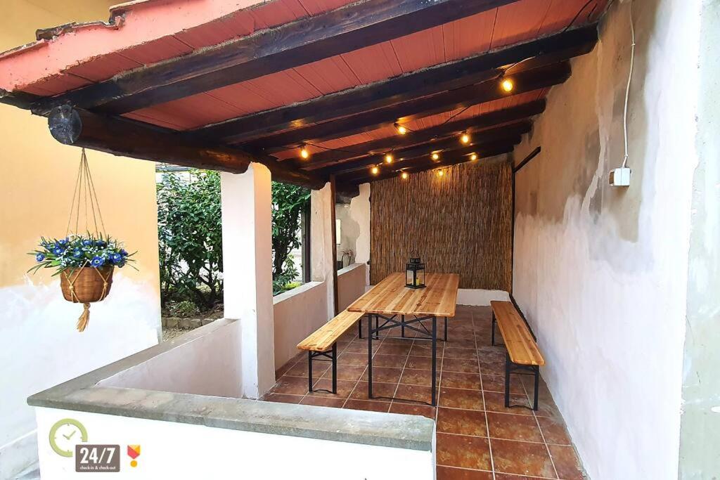 een patio met een houten tafel en banken in een gebouw bij Eco Villetta di Beppina con giardino - Self Check-in in Pratovecchio