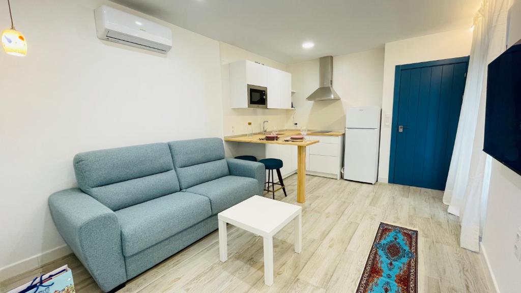 uma sala de estar com um sofá azul e uma cozinha em Apartamentos BRAVO MURILLO con garaje en centro histórico em Badajoz