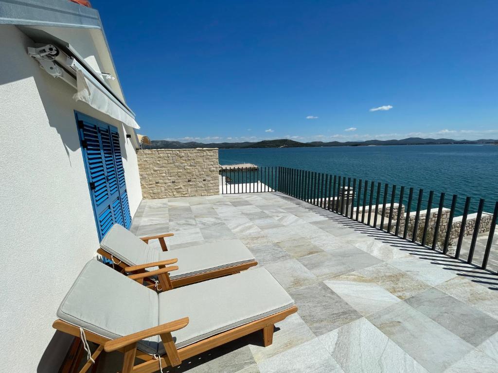 a patio with two chairs and the water at BEACHFRONT VILLA Murter in Murter