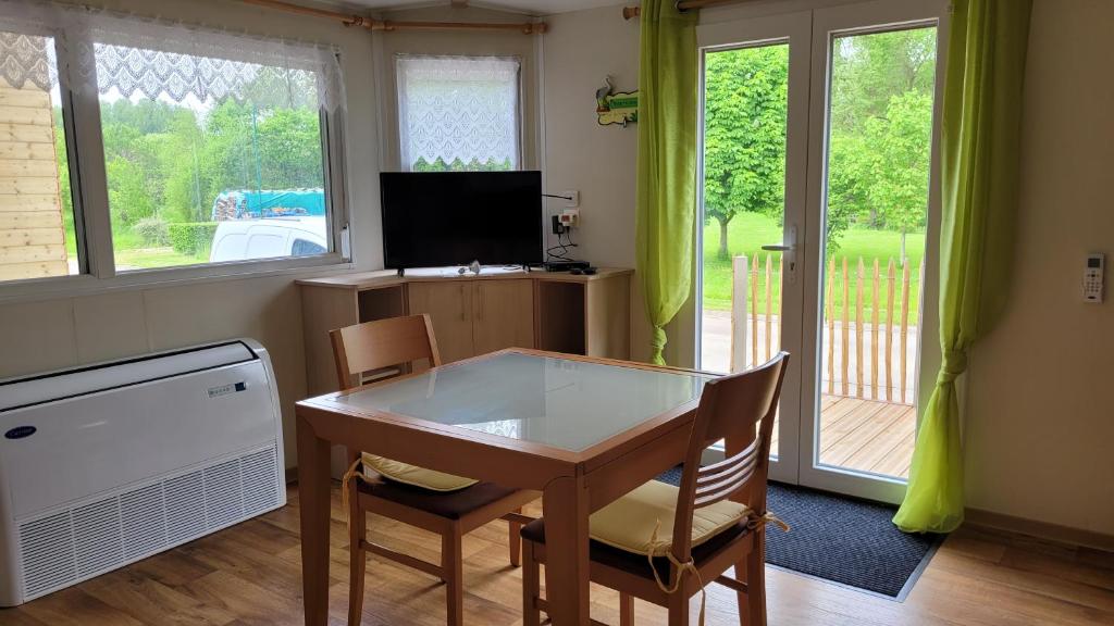 a dining room with a table and chairs and a television at Mobil home Nature in Braucourt