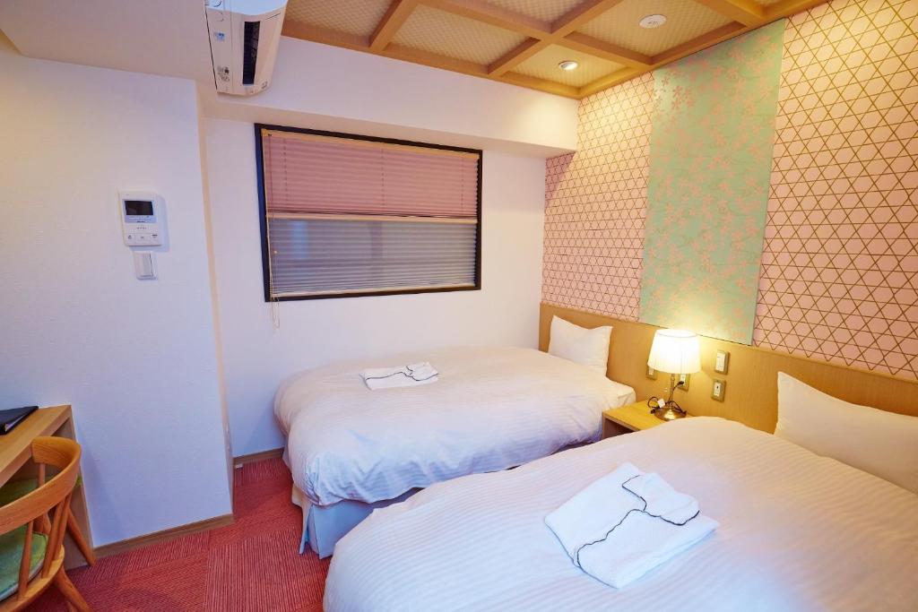 two beds in a small room with a window at Hotel Sanriiott Kitahama - Vacation STAY 33534v in Osaka