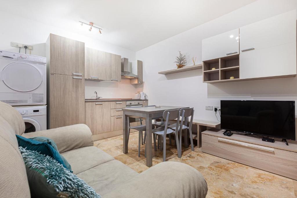 ein Wohnzimmer mit Couch und Tisch und eine Küche in der Unterkunft Designer HOME with COMFY SOFA in central Valletta by 360 Estates in Valletta