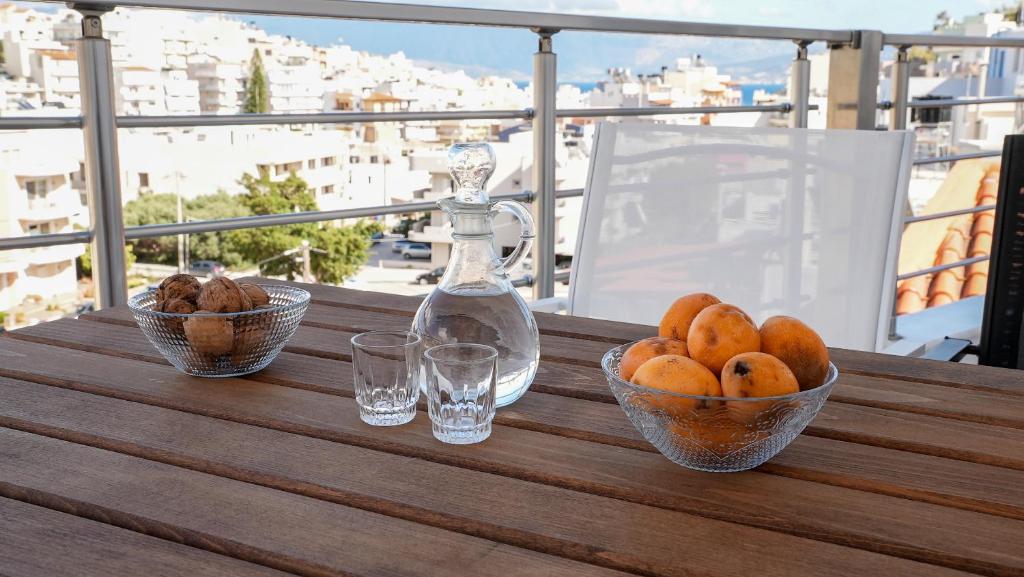 uma mesa com taças de fruta e uma garrafa na varanda em Oasis - Chic & minimal apt em Agios Nikolaos