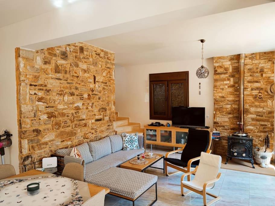 a living room with a couch and a stone wall at Вила Елена-Villa Elena in Skala Potamias