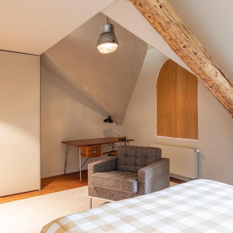 a bedroom with a bed and a chair and a table at GRAACE Suite in Luxembourg