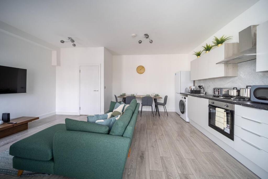 a living room with a green couch and a kitchen at Stunning 3 bedroom flat in Southend-on-sea in Southend-on-Sea