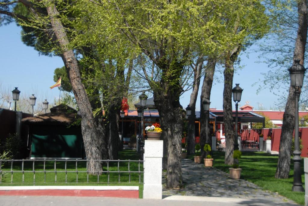 rząd drzew w parku z budynkiem w obiekcie Hotel Casa José Díaz w mieście San Agustín de Guadalix