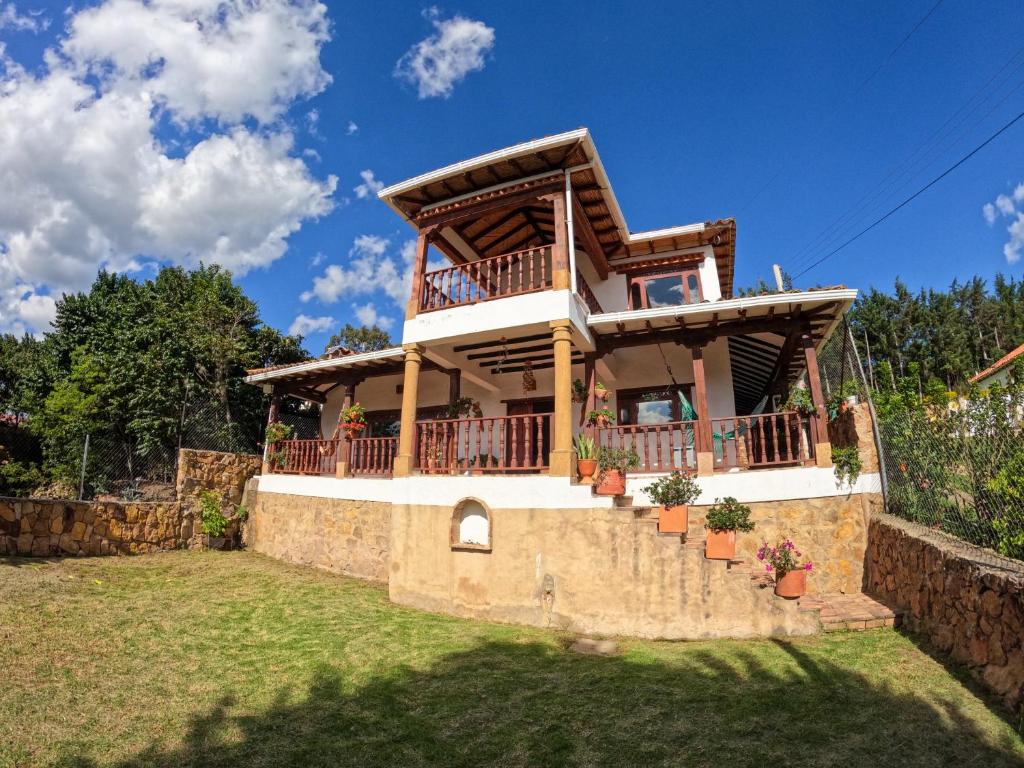 ein Haus mit einem Balkon an einer Steinmauer in der Unterkunft casa campestre el KFIR in Villa de Leyva