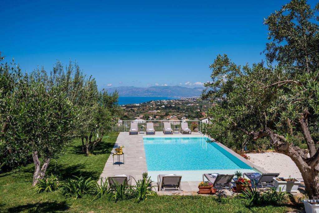 a swimming pool in a yard with chairs and trees at Villa Maria con piscina e vista mare in Castellammare del Golfo