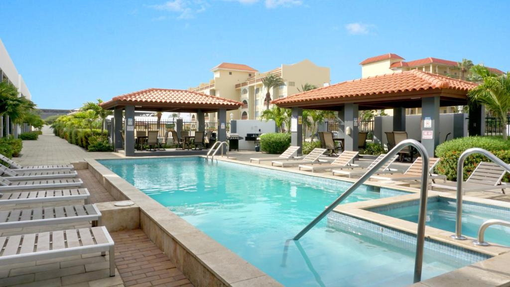 einen Pool mit Liegestühlen und ein Resort in der Unterkunft Arena Condominium Aruba in Palm-Eagle Beach