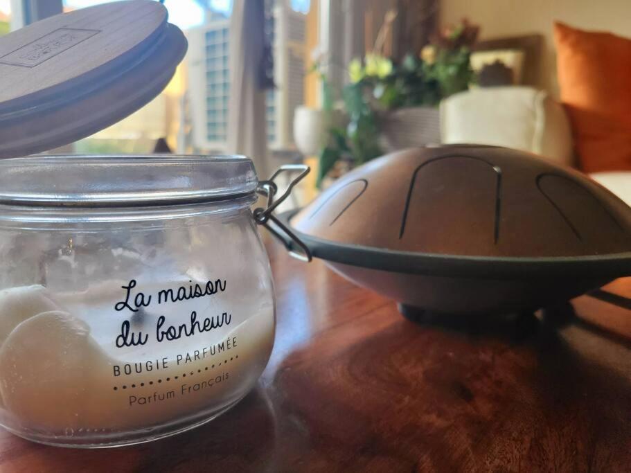 a candle in a jar on a table with a bowl at Une invitation à la détente in Nice