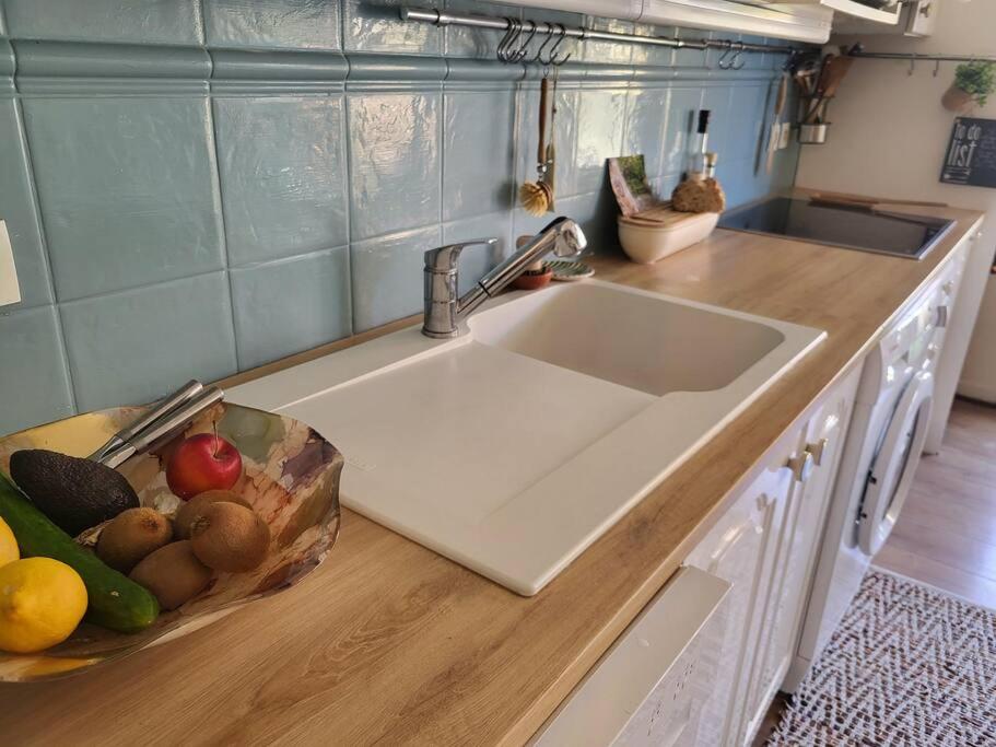a kitchen counter with a sink and a bowl of fruit at Une invitation à la détente in Nice