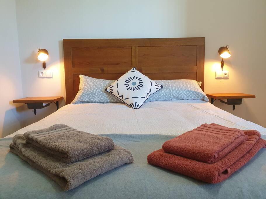 a bed with two towels and two pillows on it at Casita adosada in Vigo