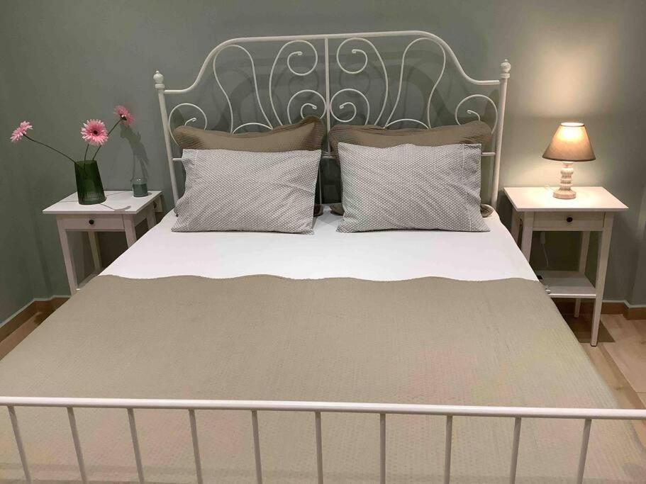 a bed with a metal headboard and two tables with flowers at N G Luxury Apartments at Nea Kallikrateia No 2 in Nea Kallikrateia