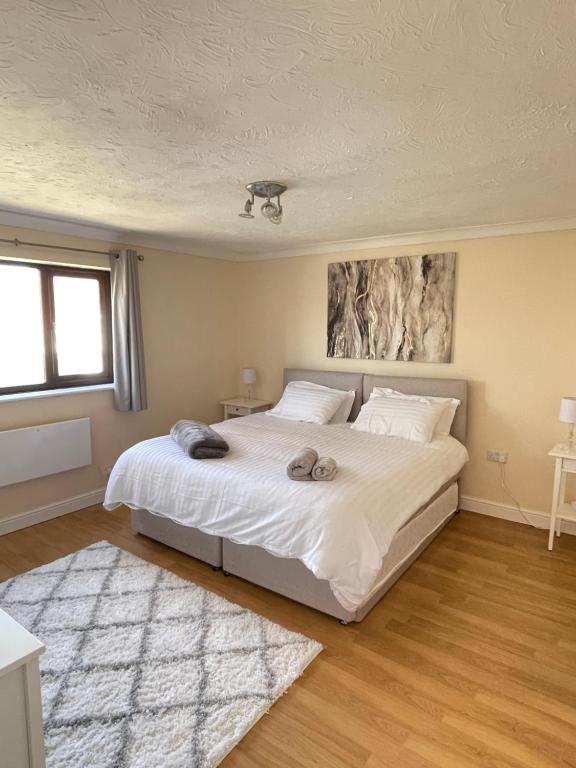 um quarto com uma grande cama branca e 2 almofadas em On Site Stays - Cosy ground floor 2 bed with Wifi and lots of Parking em Colchester