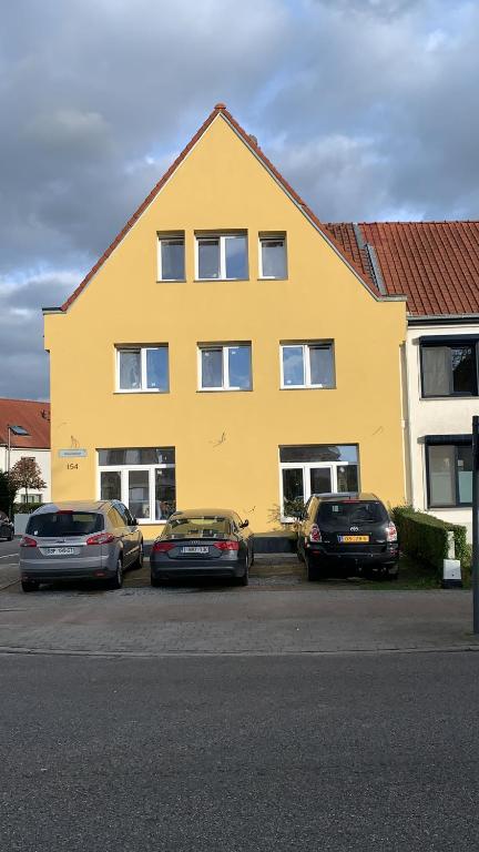 trois voitures garées devant un bâtiment jaune dans l'établissement Orange Dolce, à Zaventem