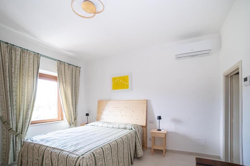 a white bedroom with a bed and a window at La Casa degli Dei in San Gimignano