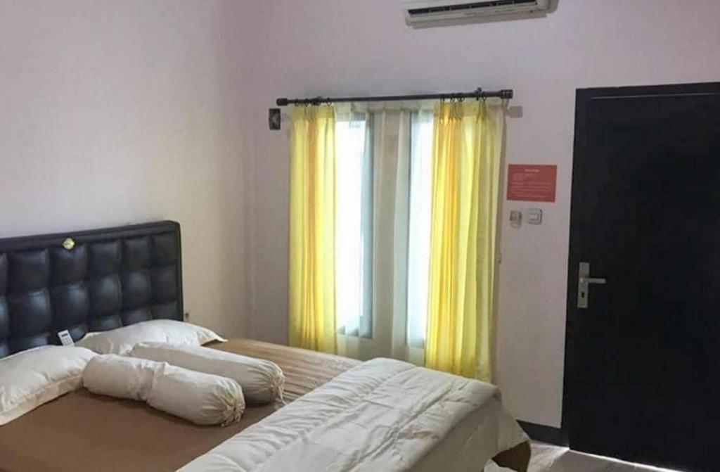 a bedroom with a bed and a window with yellow curtains at Kost Haji Naini in Merauke