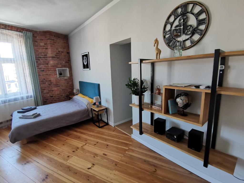 1 dormitorio con 1 cama y reloj en la pared en Apartamenty w ścisłym centrum Kupiecka-Drzewna, en Zielona Góra