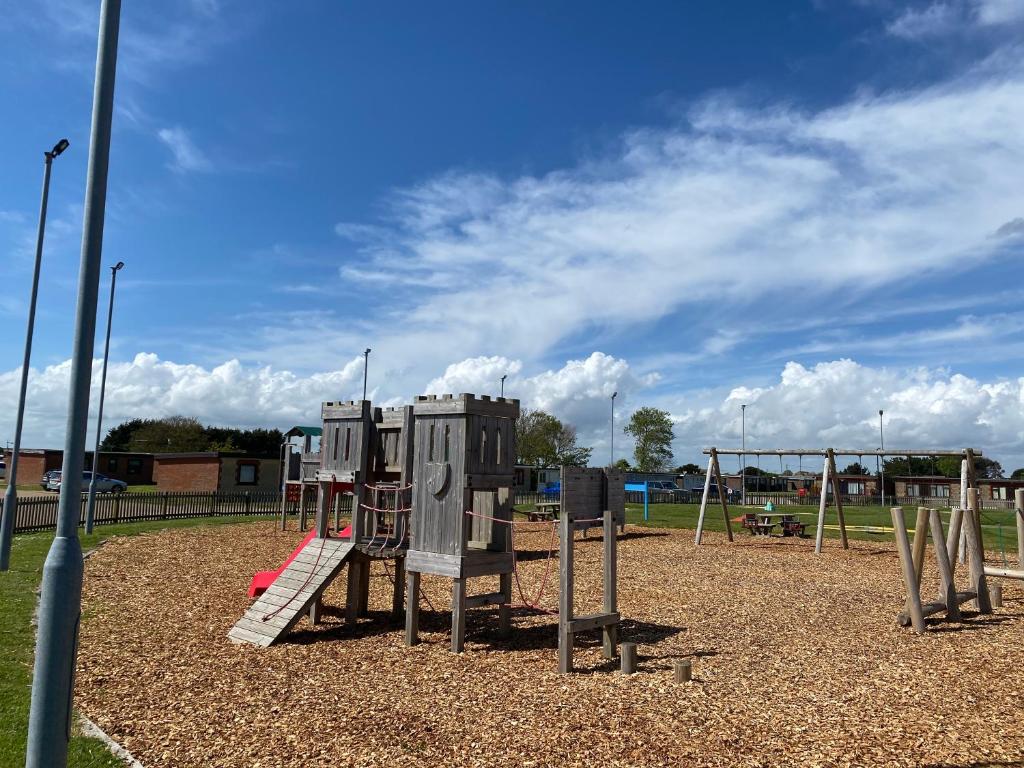 a playground with a slide and a swing set at Cosy holiday home at Romney Sands in New Romney