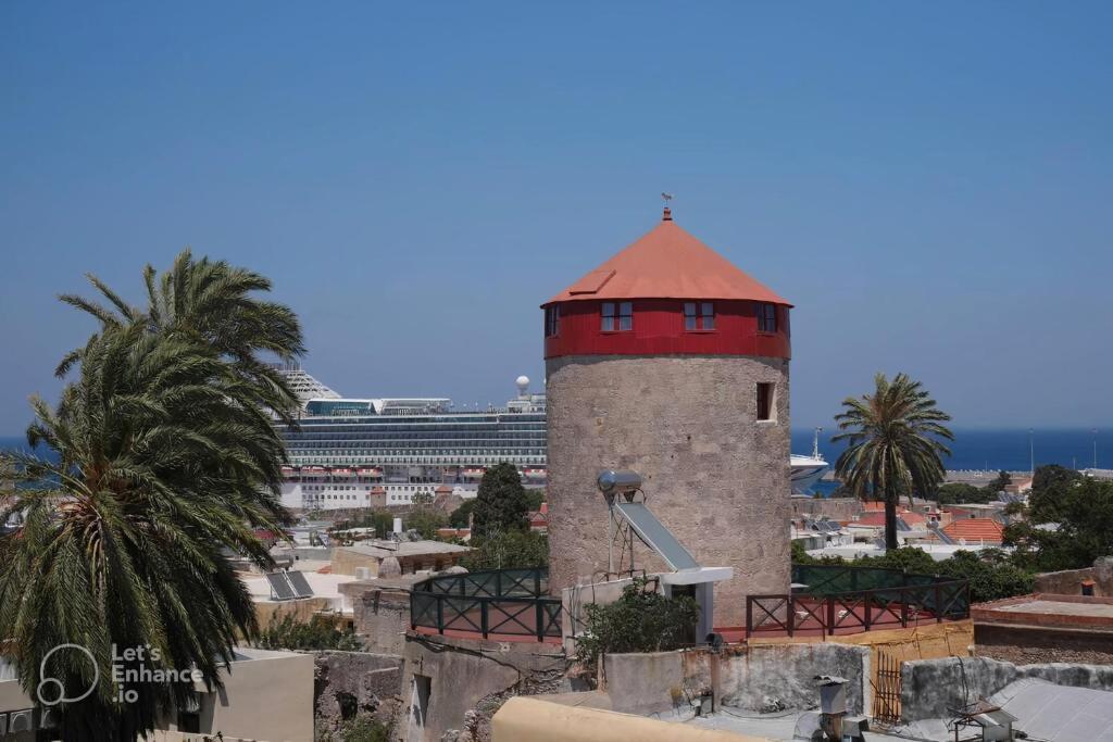 un faro con techo rojo en la cima de una ciudad en A medieval windmill tower with magnificent view, en Rodas