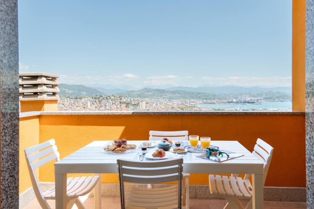 een witte tafel met stoelen en eten op een balkon bij Piccapiana Sea View Attic Flat in La Spezia