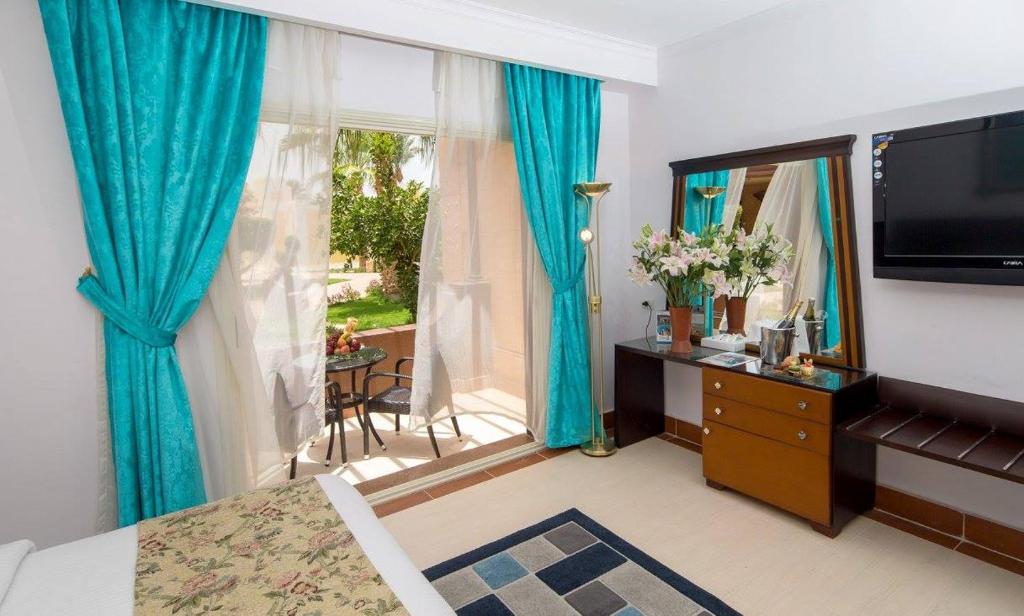 a bedroom with a large window with blue curtains at Mirage Apartments & Aqua Park in Hurghada